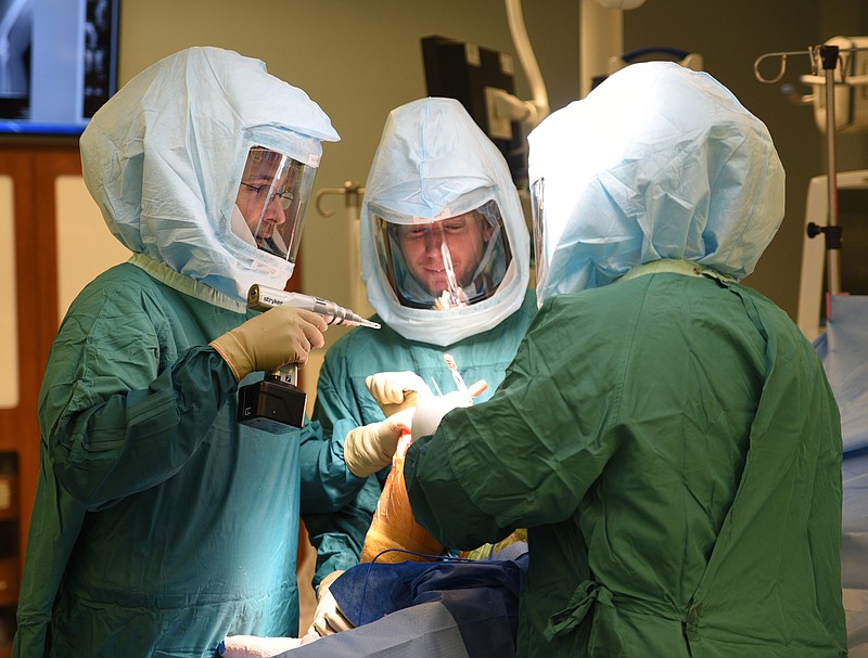 Dr. Timothy Ballard, left, assisted by Justin Sigler, center, and Mindy Loach, performs a double knee replacement Tuesday, January 17, 2016 at CHI Memorial Hospital.