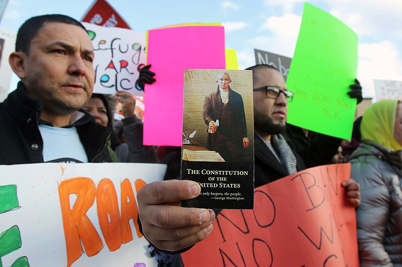 
              In this Jan. 29, 2017, rally participants Zorzy Borga, left, and Carlos Castaneda, holding a pamphlet of the US Constitution, both of Elizabeth, N.J., participate in a rally in Elizabeth outside the Homeland Security Detention Center protesting President Donald Trump's executive order banning travel to the U.S. by citizens of Iraq, Syria, Iran, Sudan, Libya, Somalia or Yemen. (Thomas E. Franklin/The Record via AP)
            