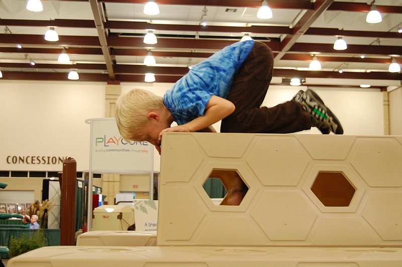 In this 2010 file photo, Zackrey Duncan peeks at Sydney Adams atop a playground tunnel built by the Chattanooga-based PlayCore company.