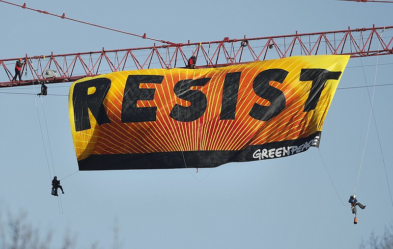 Protesters unfurl a banner that reads "Resist" at the construction site of the former Washington Post building in Washington on Wednesday after police say protesters climbed a crane at the site refusing to allow workers to work in the area. (AP Photo/Pablo Martinez Monsivais)