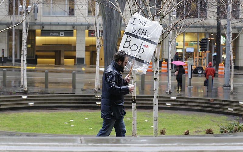 
              A person walks outside the federal courthouse in Seattle carrying a sign that reads "I'm with Bob and Immigrants," in reference to Washington state Attorney General Bob Ferguson, Friday, Feb. 3, 2017, during a hearing in federal court. A U.S. judge on Friday temporarily blocked President Donald Trump's ban on people from seven predominantly Muslim countries from entering the United States after Washington state and Minnesota urged a nationwide hold on the executive order that has launched legal battles across the country. (AP Photo/Ted S. Warren)
            