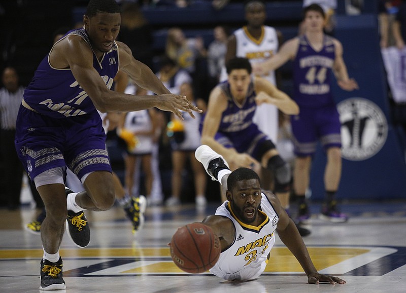 UTC forward Tre' McLean dives to save a lost ball ahead of WCU guard Haboubacar Mutombo during the Mocs' home basketball game against the Western Carolina Catamounts at McKenzie Arena on Saturday, Feb. 4, 2017, in Chattanooga, Tenn.