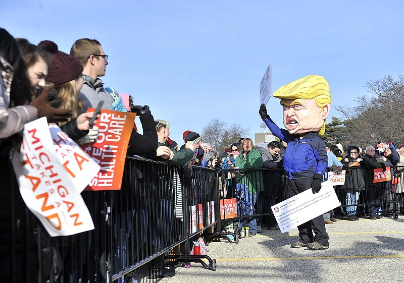 
              FILE- In a Sunday, Jan. 15, 2017 file photo, a person dressed as Donald Trump waves before a rally for health care at Macomb Community College in Warren, Mich. Detroit is gearing up to work with President Trump after receiving millions of dollars in federal grants and other support from the Obama White House. But some are concerned that Detroit won't get the same level of love from Trump as the city received from Barack Obama. (Robin Buckson/The Detroit News via AP_FILE)
            