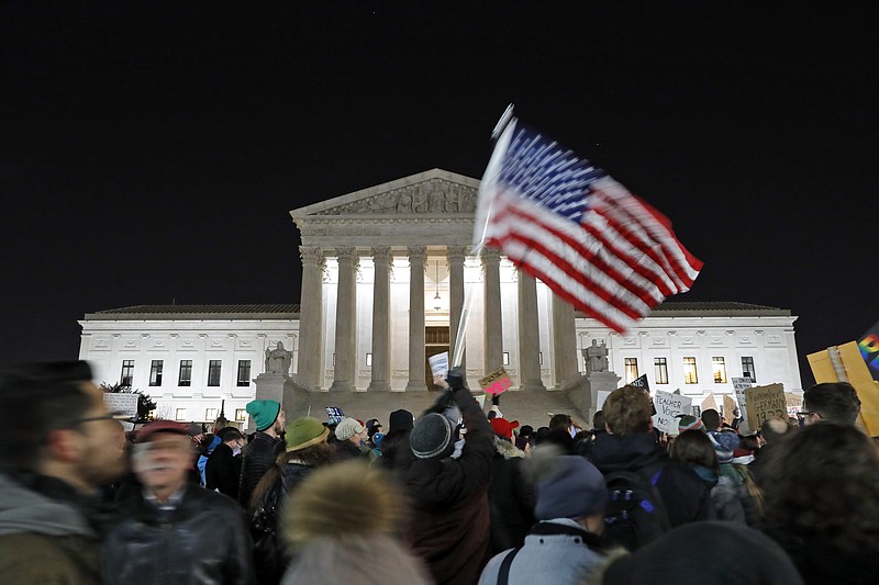 A protester waves an American flag in front of the Supreme Court.