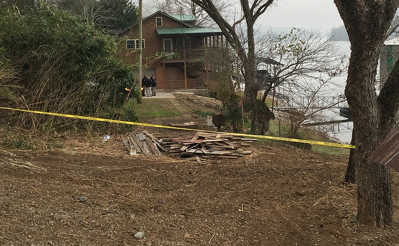 Investigators gather Monday in the parking lot of a home along Suck Creek Road where a body was discovered Monday morning.
