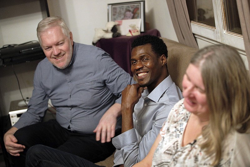 
              In this photo dated Thursday, Feb. 2, 2017, Loic Gandais, left, and his wife Murielle Gandais, right, sit in the living room with Cheikh Ahmed, a refugee from Guinea staying at their home in Palaiseau, south of Paris France. When the Gandais family decided to host a refugee at their home in a middle class neighborhood outside Paris, they assumed their guest would be a Syrian or an Iraqi fleeing war. Instead, a 25-year-old journalist with a young family in the former French colony of Guinea is the person sleeping gratefully in a spare bedroom, sharing unfamiliar food and nourishing hopes for a better life. (AP Photo/Christophe Ena)
            