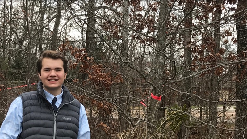 Ethan Fell stands in front of the path he is working to turn into a sidewalk for students walking to Nolan Elementary School. (Contributed photo)