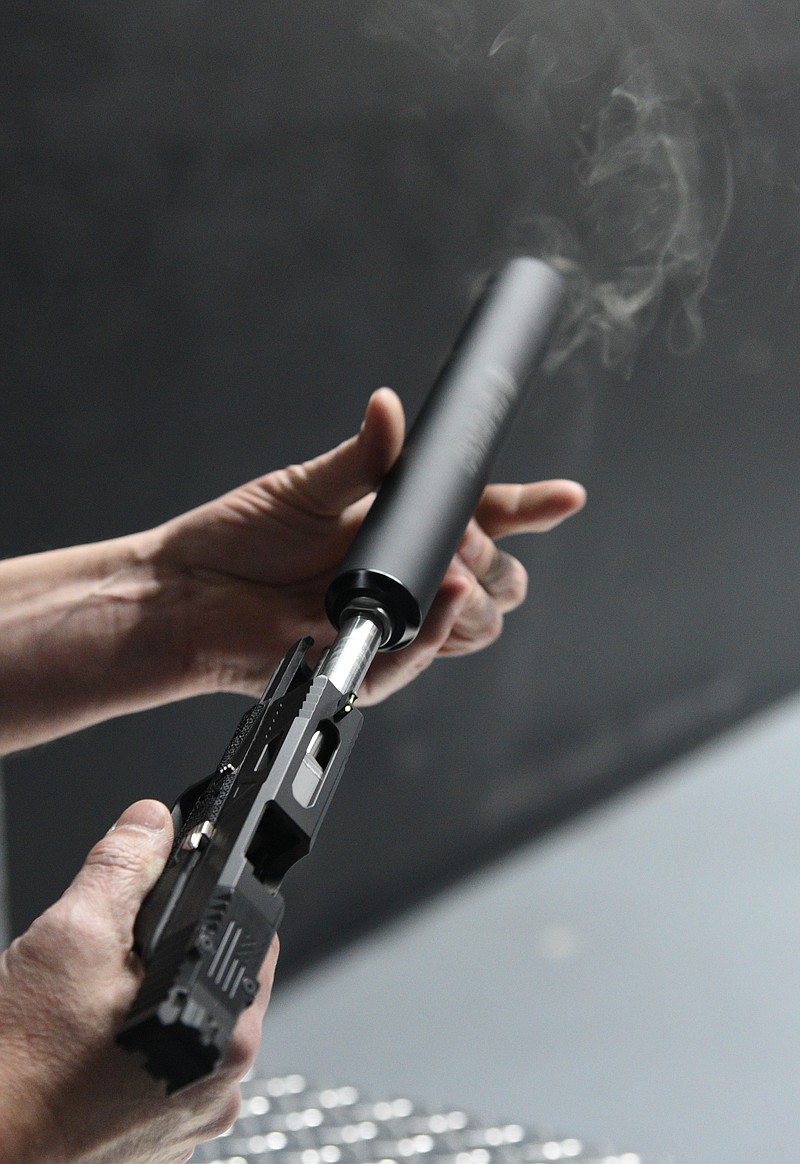 Chris Dempsey removes a silencer from a gun after firing it Monday, Feb. 13, 2017 at Shooters Depot on Shallowford Road.