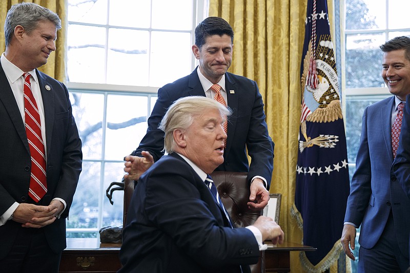 
              Rep. Bill Huizenga, R-Mich., left, and Rep. Sean Duffy, R-Wis., right, watch as House Speaker Paul Ryan of Wis. pats President Donald Trump on the back after the president signed the House Joint Resolution 41, Tuesday, Feb. 14, 2017, in the Oval Office of the White House in Washington. (AP Photo/Evan Vucci)
            