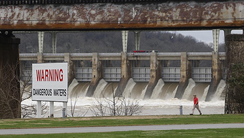 Josh Dove makes his way along the riverwalk at Chickamauga Dam as a large flow of water pours through the spillway on December 28, 2015. 