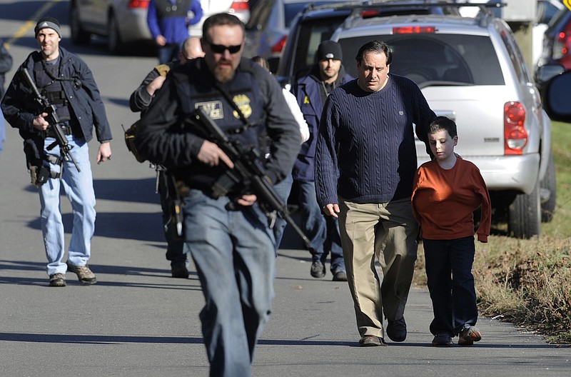 FILE - In this Friday, Dec. 14, 2012, file photo, parents leave a staging area after being reunited with their children following a shooting at the Sandy Hook Elementary School in Newtown, Conn., where Adam Lanza fatally shot 27 people, including 20 children.