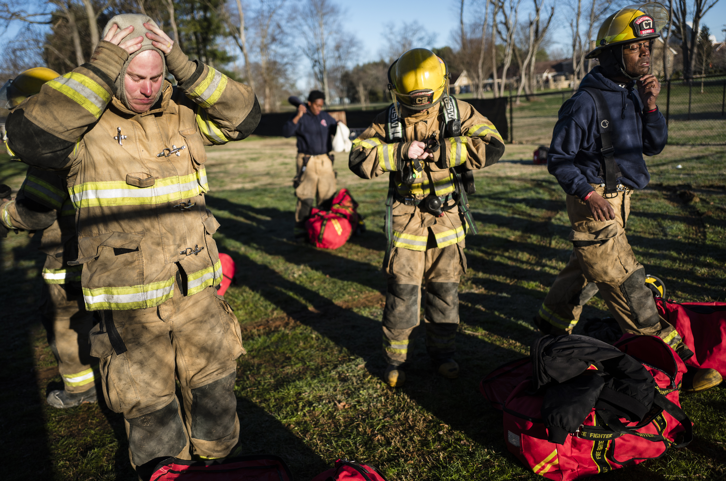 Fire recruits Scott Paone, left, Ruben Allison, center and Reginald Dowdy gear up at a live burn training event by the Chattanooga Fire Department on Robin Drive on Thursday, Feb. 16, 2017, in Chattanooga, Tenn. The fire department uses live burns as part of their fire academy training, culminating in the complete immolation of a structure.