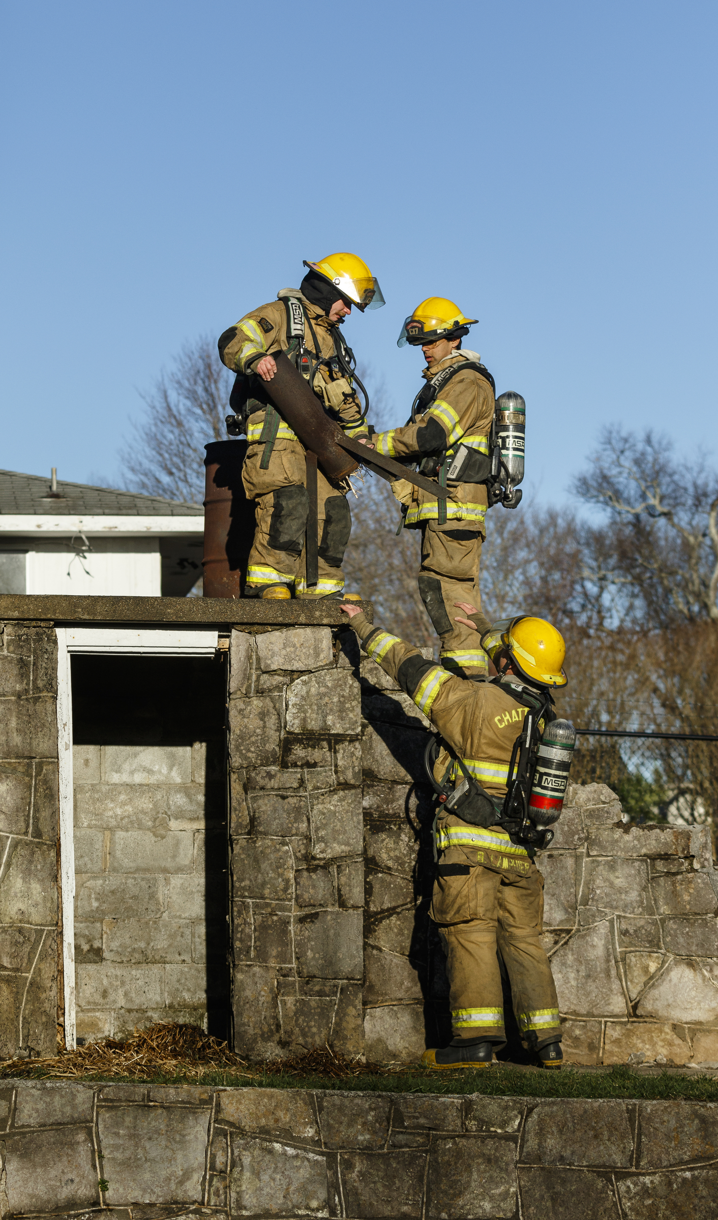 Fire recruits remove training supplies before igniting an empty structure at a live burn training event by the Chattanooga Fire Department on Robin Drive on Thursday, Feb. 16, 2017, in Chattanooga, Tenn. The fire department uses live burns as part of their fire academy training, culminating in the complete immolation of a structure.