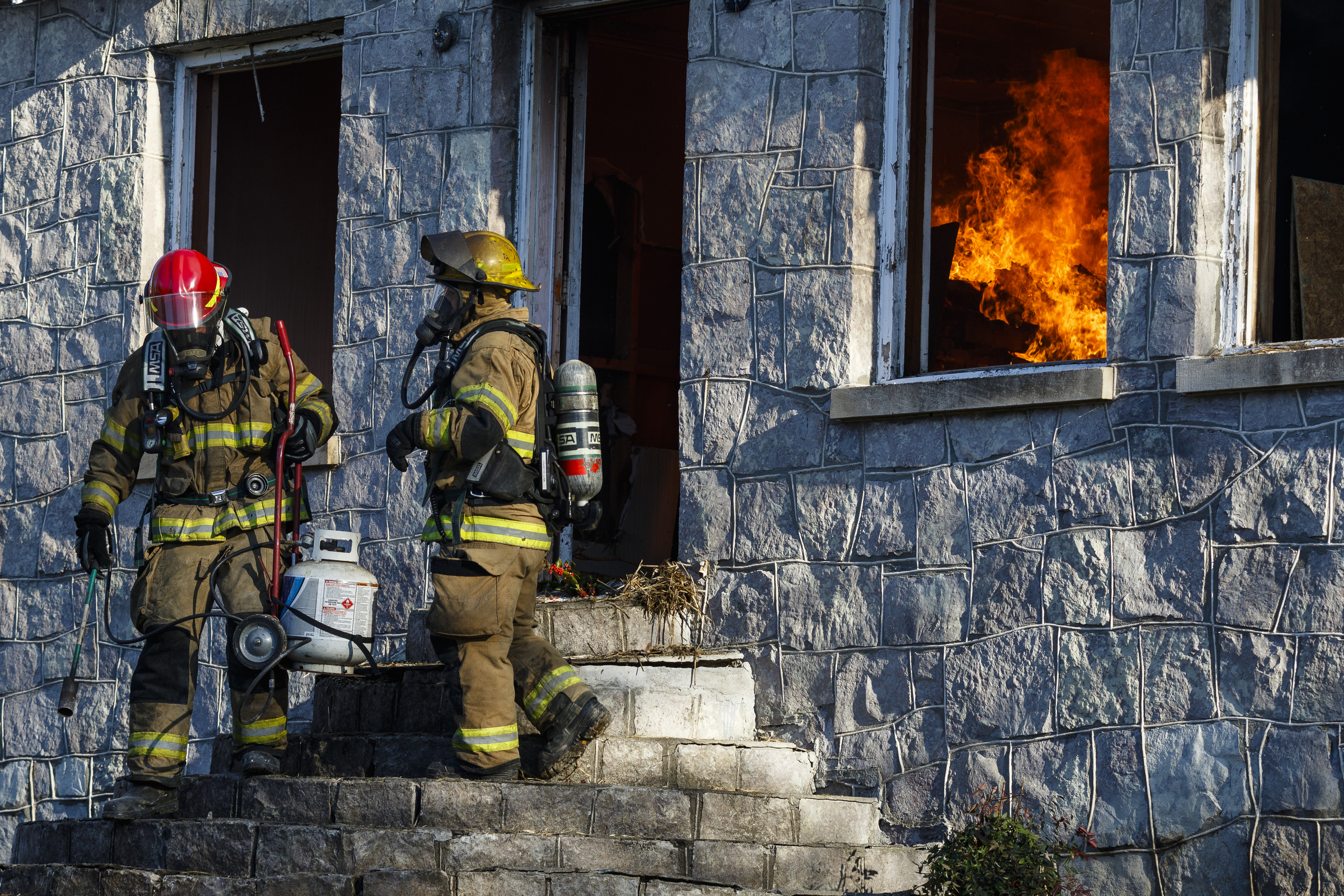 Firefighters exit after lighting kindling inside of a vacant structure at a live burn training event by the Chattanooga Fire Department on Robin Drive on Thursday, Feb. 16, 2017, in Chattanooga, Tenn. The fire department uses live burns as part of their fire academy training, culminating in the complete immolation of a structure.