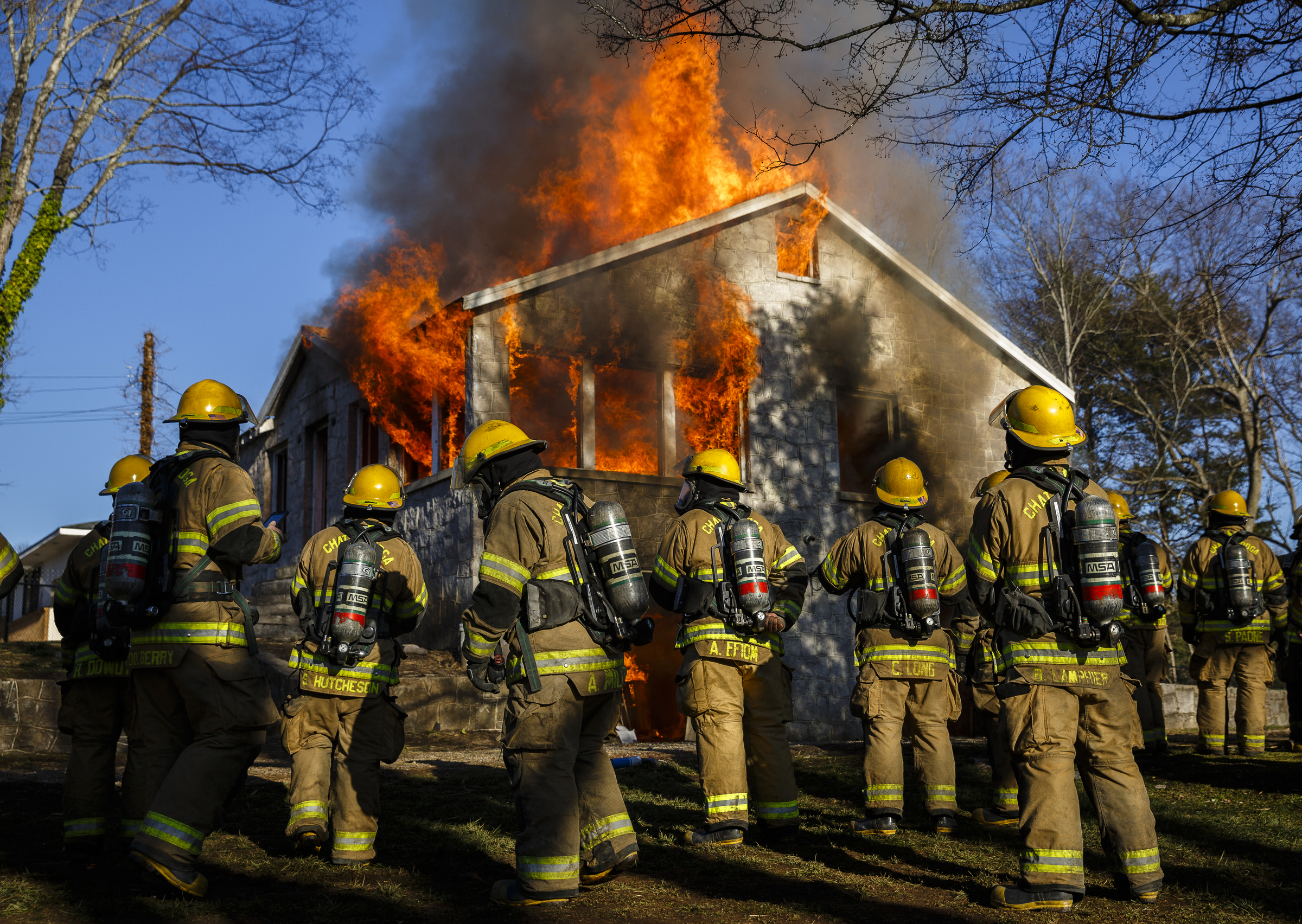 Fire recruits watch as the structure becomes fully engulfed at a live burn training event by the Chattanooga Fire Department on Robin Drive on Thursday, Feb. 16, 2017, in Chattanooga, Tenn. The fire department uses live burns as part of their fire academy training, culminating in the complete immolation of a structure.