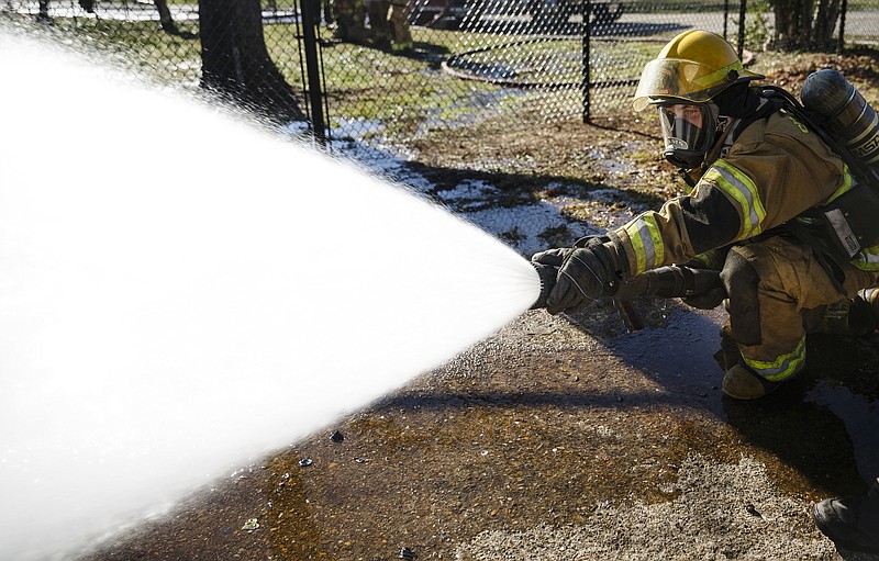 Fire recruit Adams sprays to keep the flames away from a nearby structure at a live burn by the Chattanooga Fire Department of a home on Robin Drive on Thursday, Feb. 16, 2017, in Chattanooga, Tenn. The fire department uses live burns as part of their fire academy training, culminating in the complete immolation of a structure.