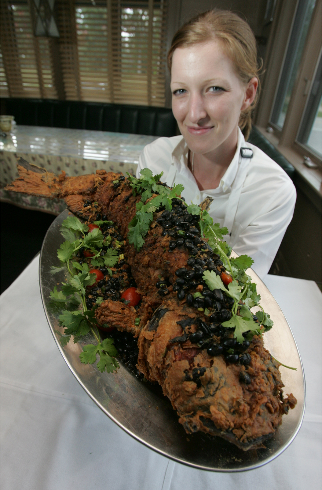 Canyon Grill Captain Sarah Reeves holds up the restaurant's signature dished called SlashNBurn, a large 3-5 pound marinated catfish, with ginger, jalpenos, and garlic stuffed into slices made along the side. The SlashNBurn has been on the restaurant's menu since it opened and can easily serve two people or as an appetizer for larger groups.