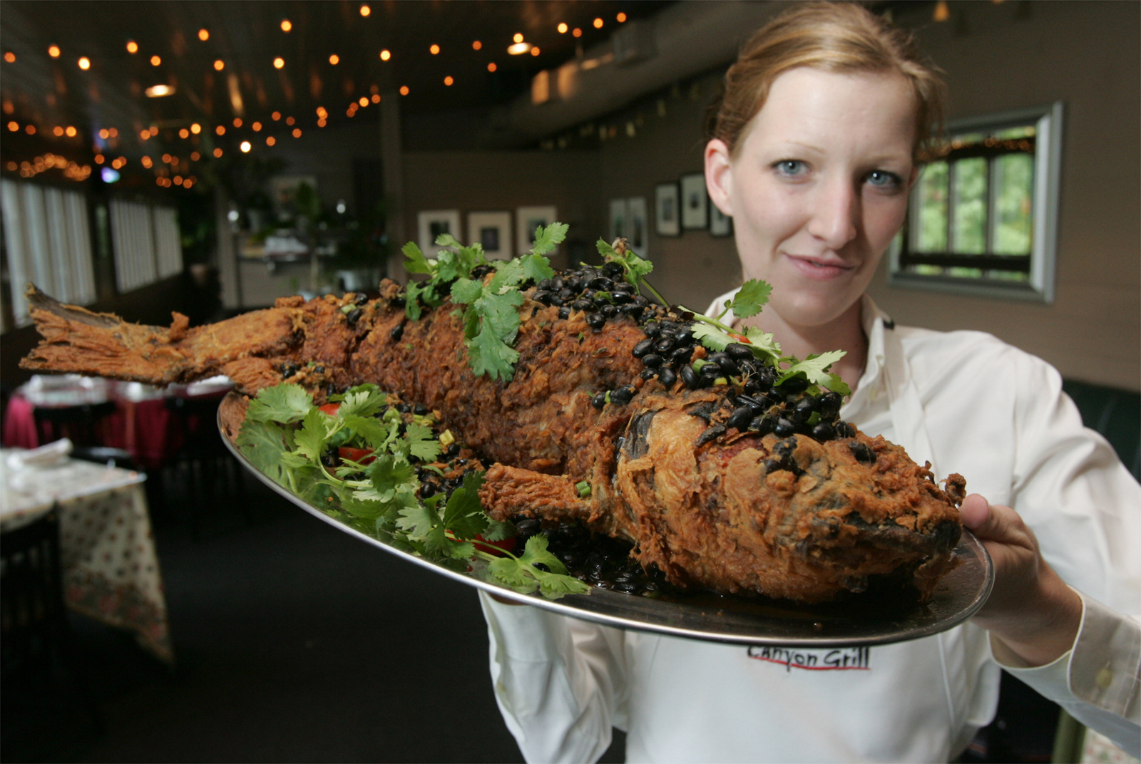 Canyon Grill Captain Sarah Reeves holds up the restaurant's signature dished called SlashNBurn, a large 3-5 pound marinated catfish, with ginger, jalpenos, and garlic stuffed into slices made along the side. The SlashNBurn has been on the restaurant's menu since it opened and can easily serve two people or as an appetizer for larger groups.