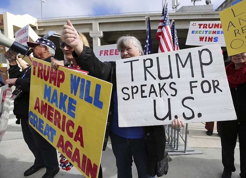 
              FILE - In this Feb. 4, 2017, file photo, a woman gives a thumbs up in Los Angeles, Calif., as demonstrators in favor of President Donald Trump's executive order banning travel to the U.S. from seven primarily Muslim nations stand across the street from the Tom Bradley International Terminal at Los Angeles International Airport. President Donald Trump's administration said in court documents on Thursday, Feb. 16, 2017, it wants an end to the legal fight over its ban on travelers from seven predominantly Muslim nations and will instead issue a replacement ban.  (AP Photo/Reed Saxon, File)
            