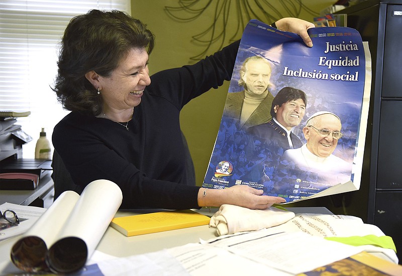 
              In this photo taken Feb. 9, 2017, Silvia Camarillo holds a poster from a meeting she attended in Bolivia in her office at St. Jude's Catholic Church in Ceres, Calif. Camarillo attended the World Meeting of Popular Movements in Bolivia and will be at the upcoming four-day meeting the Vatican is co-hosting in Modesto where clergy and grassroots activists are expected to strategize ways to resist White House policies targeting immigrants, refugees and religious minorities. (Joan Barnett Lee/The Modesto Bee via AP)
            