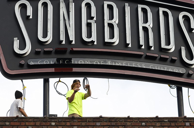 Donnie Wassom, center, and another worker direct the crane installation of a sign for the Songbirds guitar museum at the Chattanooga Choo Choo off Station Street on Thursday, Nov. 3, 2016, in Chattanooga.