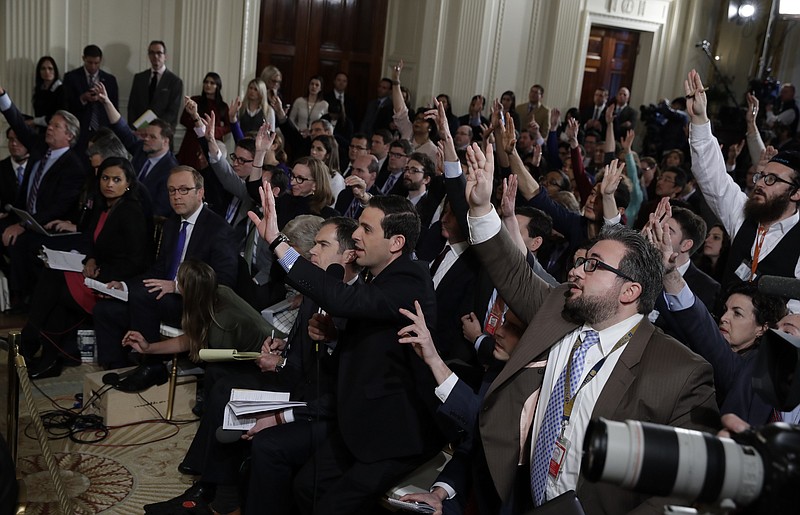 Desperate reporters raise their hands during President Donald Trump's Thursday news conference in the East Room of the White House in Washington.