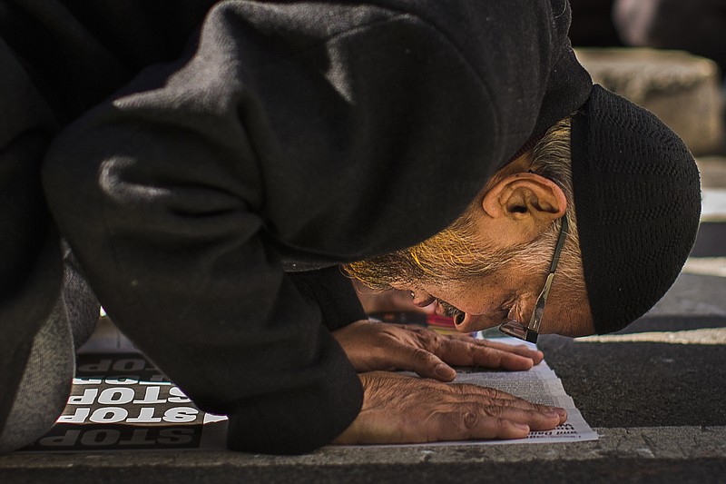 
              A man preys during a rally against President Donald Trump's executive order banning travel from seven Muslim-majority nations, in New York's Times Square, Sunday, Feb. 19, 2017. (AP Photo/Andres Kudacki)
            