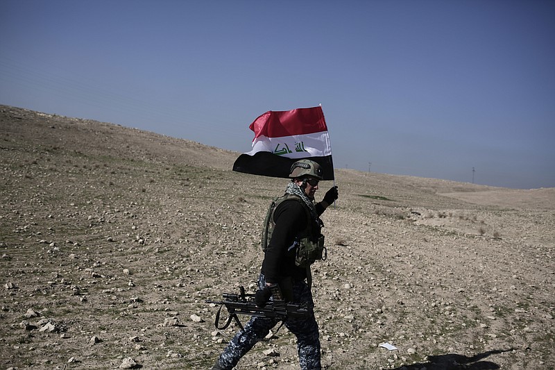 
              A member of the Iraqi federal police carries an Iraqi flag during a battle against the Islamic State, in Hamam al-Alil, Iraq, Sunday, Feb. 2017. U.S.-backed Iraqi forces launched a large-scale military operation on Sunday to dislodge Islamic State militants from the western half of Mosul city. (AP Photo/Bram Janssen)
            