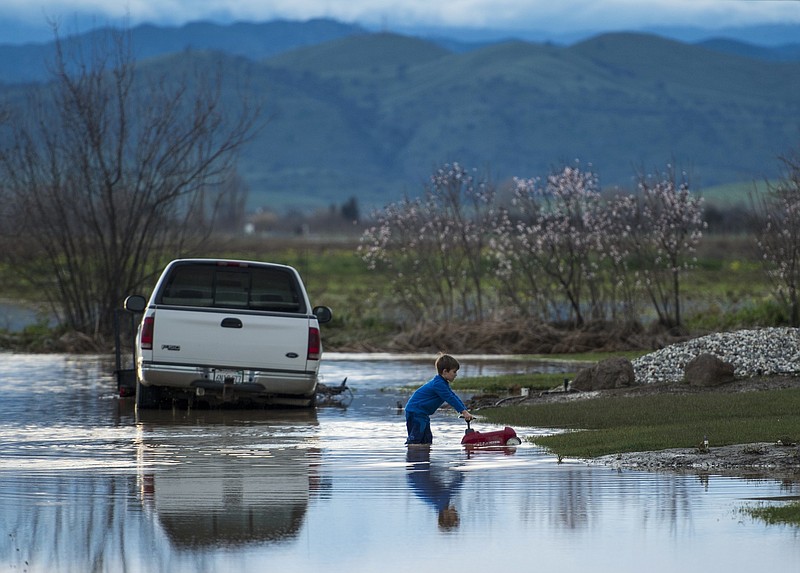 
              Barr Torrens, 5, plays in flooded neighborhood streets after a deluge of rain and water-runoff flooded much of Maxwell, Calif., Saturday, Feb. 18, 2017. Northwest of Sacramento, several hundred people were evacuated Saturday as overflowing creeks turned the town of Maxwell into a brown pond, with some homes getting 2 feet of water. (Andre Seng/The Sacramento Bee via AP)
            