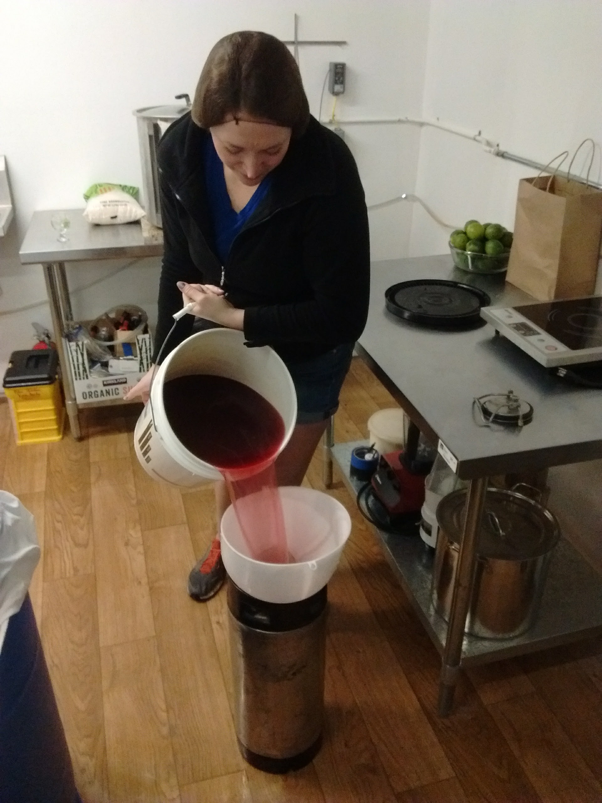 Employee Sloane Lepaige pours kombucha from a 5-gallon bucket through a filter and into a keg.