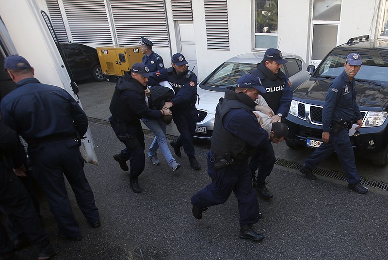 
              In this Sunday, Oct. 16, 2016 file photo, Montenegrin police officers escort people suspected of planning armed attacks after the parliamentary vote in Podgorica, Montenegro. Montenegro's special prosecutor  Milivoje Katnic, has accused Russia and its secret service operatives of plotting a coup attempt that included plans to kill the small Balkan country's former prime minister, Milo Djukanovic, following an investigation. (AP Photo/Darko Vojinovic, File)
            