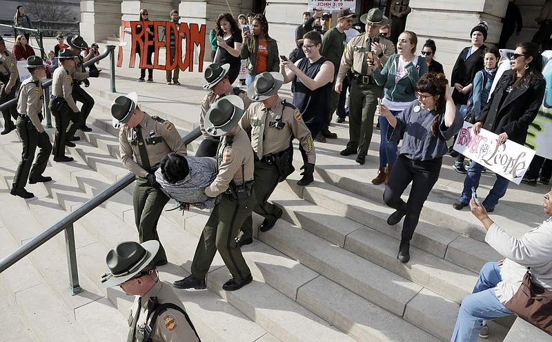 In this Friday, Jan. 20, 2017, file photo, a protester is carried away from the state Capitol building in Nashville, Tenn. Protests around the state Capitol in Nashville have some Republicans calling for a crackdown on demonstrators and for resurrecting more stringent security requirements for entering the legislative office complex. Democrats are pushing back against those calls, arguing that access to the legislators shouldn't be curtailed only because many of the protesters oppose the policies of Republican President Donald Trump on issues including immigration, race, abortion and LGBT rights. (AP Photo/Mark Humphrey, File)