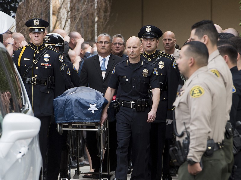 
              Whittier Police Chief Jeff Piper, center right, along with an honor guard wheel the gurney with a fallen officer's body at UCI Medical Center in Orange, Calif., Monday, Feb. 20, 2017. A California police officer was killed and another wounded in a shooting Monday while they were trying to help a man who had been in a traffic accident in Whittier, officials said. (Sam Gangwer/The Orange County Register via AP)
            