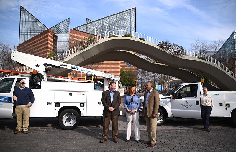 David Johnson, chief information officer for the Electric Power Board, Valoria Armstrong, president of Tennessee American Water Company, and Larry Buie, region director for Chattanooga Gas, center, from left, gather Tuesday, Feb. 21, 2017 in front of the Tennessee Aquarium to offer tips on how consumers can protect themselves from utility worker imposters. Brandon Holmes, left, and Becky Green, right, stand with utility vehicles.