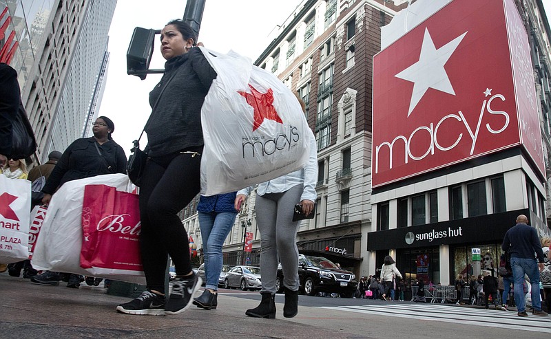 
              FILE - In this Nov. 27, 2015, file photo, shoppers carry bags as they cross a pedestrian walkway near Macy's in Herald Square in New York. Macy's Inc. is reported fiscal fourth-quarter net income of $475 million on Tuesday, Feb. 21, 2017. (AP Photo/Bebeto Matthews, File)
            