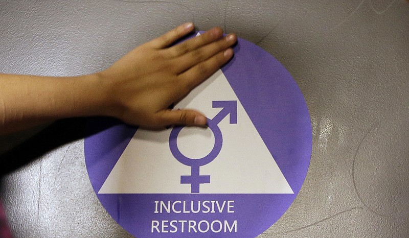 
              FILE - In this May 17, 2016 file photo, a new sticker is placed on the door at the ceremonial opening of a gender neutral bathroom at Nathan Hale High School in Seattle. A government official says the Trump administration will revoke guidelines that say transgender students should be allowed to use bathrooms and locker rooms matching their chosen gender identity.  (AP Photo/Elaine Thompson, File)
            