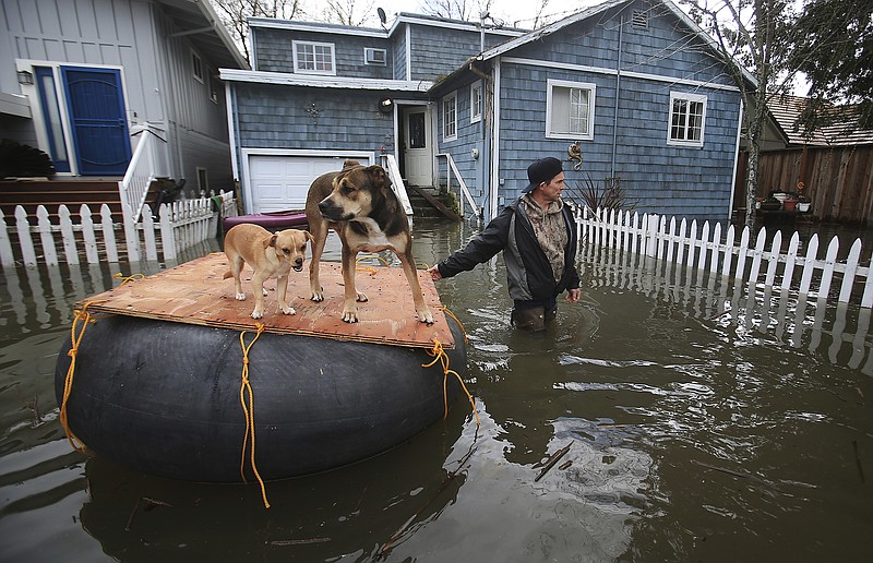 
              James Fipps takes his dogs for a walk on a makeshift raft as Clear Lake continues to inundate homes with flooding, Tuesday Feb. 21, 2017, in Lakeport, Calif.  (Kent Porter/The Press Democrat via AP)
            