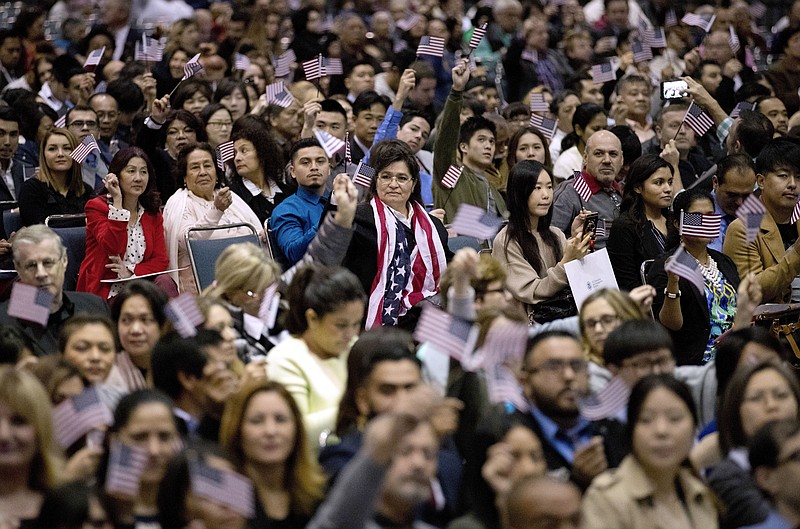 FILE - In this Wednesday, Feb. 15, 2017, file photo, people wave U.S. flags during a naturalization ceremony at the Los Angeles Convention Center, in Los Angeles. (AP Photo/Jae C. Hong, File)
            