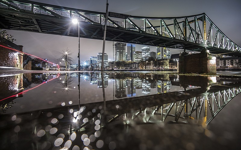 
              The Eiserne Steg bridge is reflected in a puddle before dawn in  Frankfurt, Germany, Tuesday, Feb. 21, 2017. (Frank Rumpenhorst/dpa via AP)
            