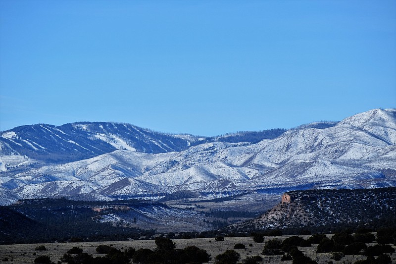 The Jemez mountain range, part of the Southern end of the Rocky Mountains, looms large over mesas in the Santa Clara Canyon.