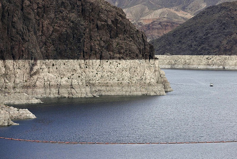 
              FILE – In this April 16, 2013 file photo, a "bathtub ring" marks the high water mark as a recreational boat approaches Hoover Dam along Black Canyon on Lake Mead, the largest Colorado River reservoir, near Boulder City, Nev. Scientists say global warming may already be shrinking the Colorado River and could reduce its flow by more than a third by the end of the century. (AP Photo/Julie Jacobson, File)
            