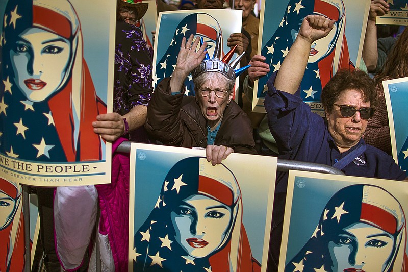 
              In this Feb. 19, 2017, file photo, people carry posters during a rally against President Donald Trump's executive order banning travel from seven Muslim-majority nations, in New York's Times Square. Trump’s travel ban has been frozen by the courts, but the White House has promised a new executive order that officials say will address concerns raised by judges that have put the policy on hold.
The first order was met by legal challenges, confusion at airports worldwide and mass protests, but the White House has forecast smoother sailing the second time around.  (AP Photo/Andres Kudacki)
            