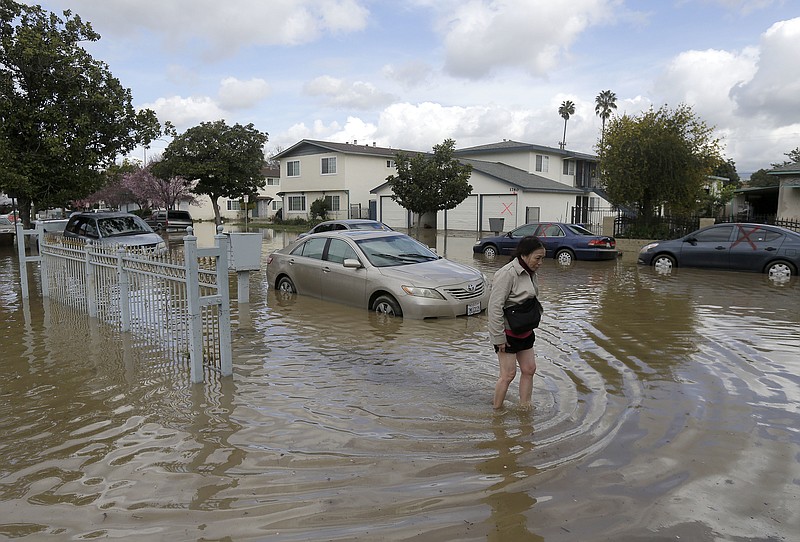 
              Hien Nguyen walks through flooded waters on Welch Avenue in San Jose, Calif., Wednesday, Feb. 22, 2017. Rising floodwaters sent thousands of residents fleeing inundated homes in San Jose and forced the shutdown of a major freeway Wednesday. (AP Photo/Jeff Chiu)
            