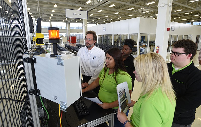 Staff file photo by Angela Lewis Foster Technical training supervisor Albert Graser, left, looks on as students Adriana Garcia, Janeequa Hemphill, Kaylee Hensley, and Joseph Miller, from left, learn about failure analysis on robots last fall at Volkswagen Academy.