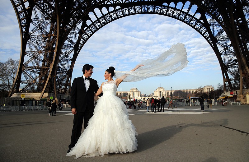 
              FILE - In this file photo dated Friday, Dec. 16, 2016, Rodrigo and Nancy from Mexico, pose for a photographer under the Eiffel Tower as they are on honeymoon in Paris.  Paris Mayor Anne Hidalgo has pushed back at U.S. President Donald Trump for insulting the romantic city of Paris, tweeting about celebrating the attractiveness of Paris and marking the increased number of reservations from American tourists.  (AP Photo/Christophe Ena, FILE)
            