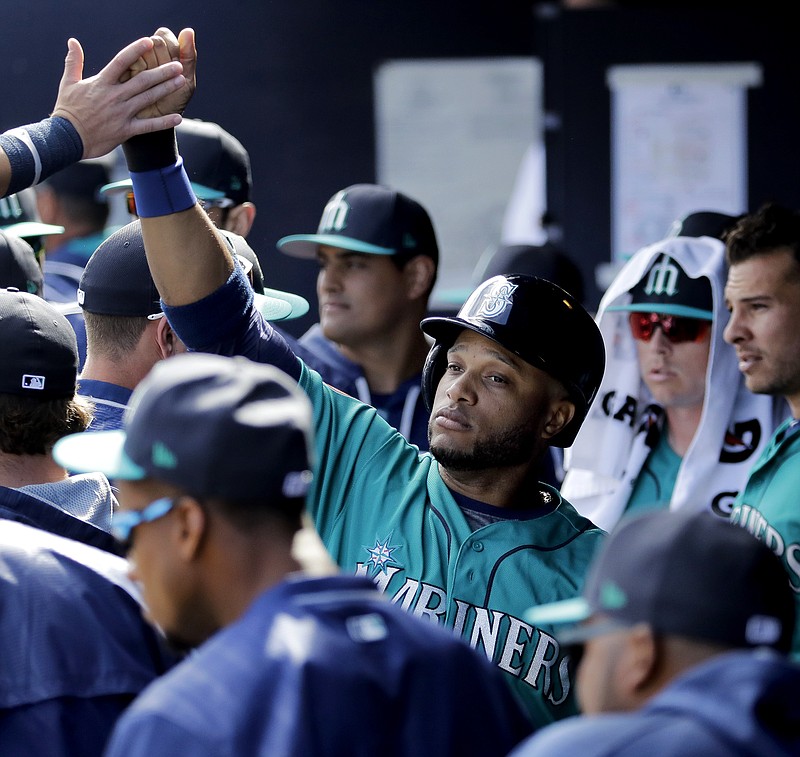 
              Seattle Mariners' Robinson Cano celebrates in the dugout after scoring when Tyler O'Neill was walked with the bases loaded during the third inning of a spring training baseball game against the San Diego Padres, Sunday, Feb. 26, 2017, in Peoria, Ariz. (AP Photo/Charlie Riedel)
            