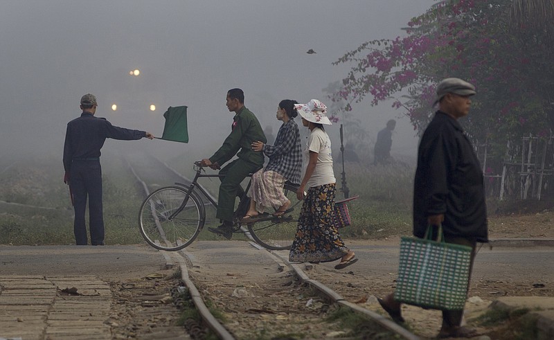 
              FILE - In this Feb. 8, 2013 file photo, a railway signalman waves a green flag indicating a train to proceed as a man rides a bicycle on the level-crossing close to a suburban train station of Yangon, Myanmar. Developing countries in Asia and the Pacific will need to invest up to $1.7 trillion a year, or $26 trillion through 2030, to meet their infrastructure needs and to maintain the region's growth momentum — more than double the previous estimate in 2009, an Asian Development Bank report said Tuesday, Feb. 28, 2017. (AP Photo/Gemunu Amarasinghe, File)
            