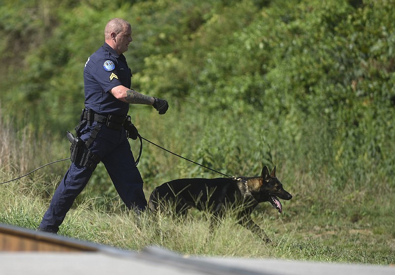 A Chattanooga police officer walks his K9 back to the car after apprehending Robert Harris, a Moccasin Bend Mental Health Institute escapee accused of two counts of child rape, near Signal Mountain Road last August.