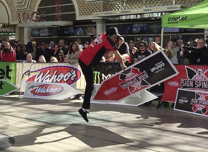 
              In this photo taken Friday, Feb. 24, 2017, Clint Hartman, a sign spinner from Portland, Ore., performs a routine in downtown Las Vegas during the annual World Sign Spinning Championships. In multiple heats with rap, hip-hop and pop tunes blasting, more than 100 competitors twirled the arrow-shaped sign in front of a cheering crowd. (AP Photo/Regina Garcia Cano)
            