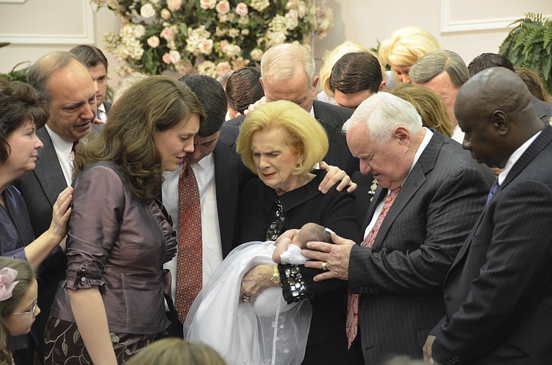 In this 2012 photo provided by a former member of the church, Word of Faith Fellowship leader Jane Whaley, center, holds a baby, accompanied by her husband, Sam, center right, and others during a ceremony in the church's compound in Spindale, N.C. From all over the world, they flocked to this tiny town in the foothills of the Blue Ridge Mountains, lured by promises of inner peace and eternal life. What many found instead: years of terror _ waged in the name of the Lord. (AP Photo)

